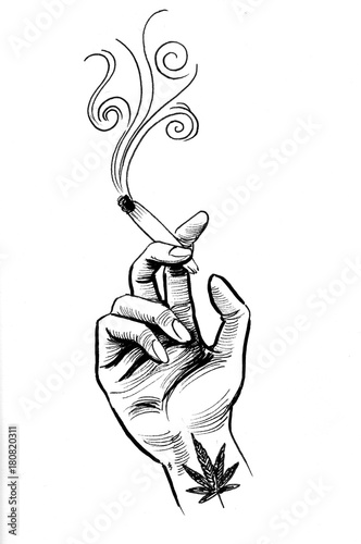 Hand with a smoking marijuana joint and a cannabis leaf tattoo on a ...