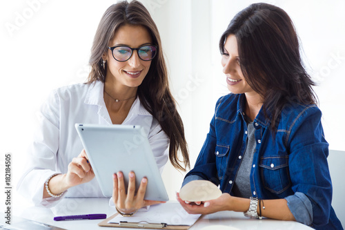 Doctor and her patient choosing mammary prosthesis in the office.