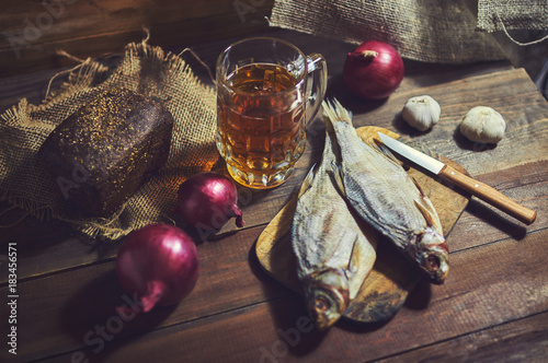 Obraz Fotograficzny Smoked fish, rye bread, garlic and glass of beer on a wooden background