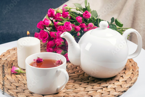 krautertee-kerze-teekanne-und-schone-rosen-auf-dem-tisch
