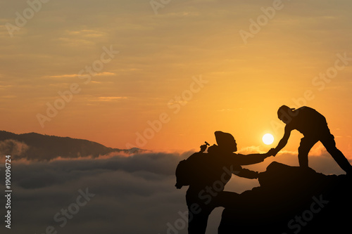 Two friends helping each other and with teamwork trying to reach the top of the mountains