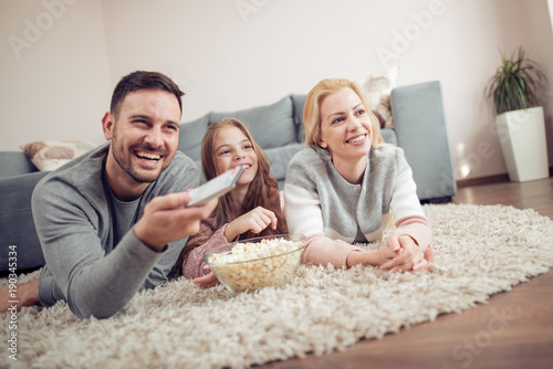 Smiling young family watching TV together.