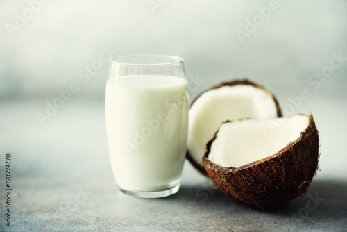 molkerei-der-kokosnuss-vegan-milch-nicht-in-den-glas-und-kokosnuss-fuit-halften-auf-grauem-konkretem-hintergrund-mit-kopienraum-vegetarisches-essen-konzept