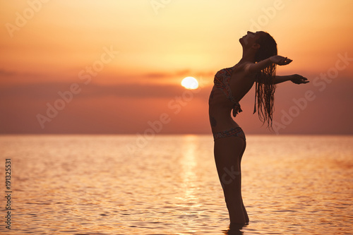 silueta-de-una-hermosa-nina-sexual-contra-el-mar-y-la-puesta-del-sol-feliz-mujer-se-encuentra-en-el-mar-con-las-manos-abiertas-y-disfruta-de-unas-vacaciones-de-verano