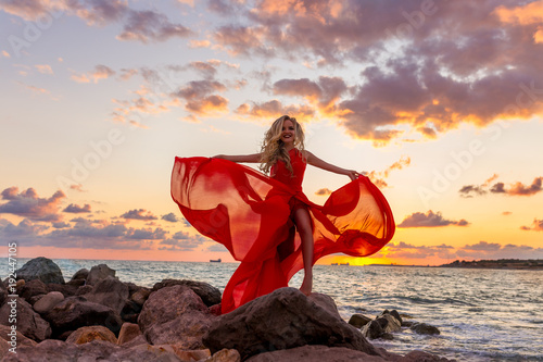 hermosa-joven-rubia-sexy-posando-en-vestido-rojo-de-noche-en-el-muelle-de-mar-en-la-puesta-del-sol