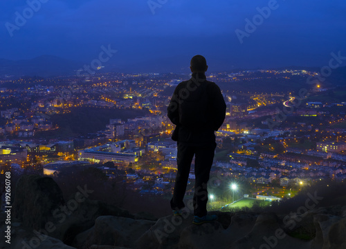 Silhouette of man looking above the city in the night