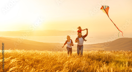 pere-de-famille-heureuse-de-mere-et-enfant-fille-lancer-un-cerf-volant-sur-la-nature-au-coucher-du-soleil