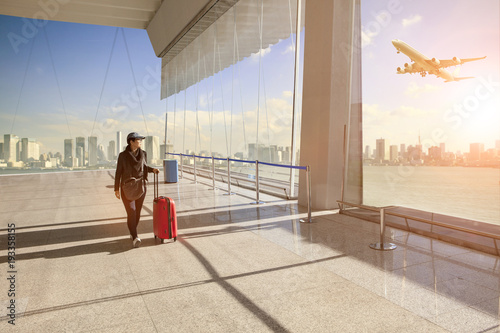 femme-voyageant-avec-bagages-appartenant-a-pied-dans-l-39-aerogare-et-l-39-avion-de-passagers-survolant-la-ville