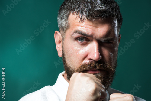 Handsome bearded boxer isolated on a green background. Karate, judo, aikido, taekwondo - oriental single combat. Closeup of male karate fighter hands. © Svitlana
