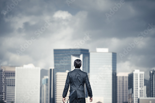 Man standing in the big city with storm clouds over head. Conquering adversity, challenging yourself concept.