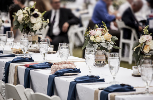 Table set up for wedding reception with people out of focus in background. © Wollwerth Imagery