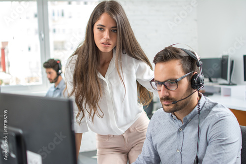 Customer support workers solving problems together on client's online account in call centre office.