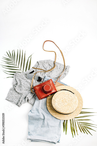 Woman fashion travel flatlay. Retro camera, straw, shorts, sunglasses and tropical palm leaf. Top view, flat lay.