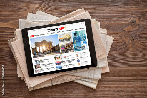 Tablet with news website on stack of newspapers. All contents are made up. © Kaspars Grinvalds