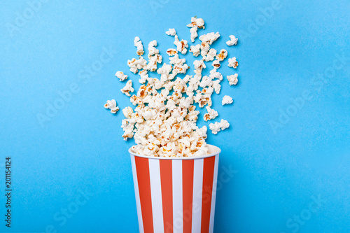 Spilled popcorn and paper bucket in red strip on blue background. Copy space for text