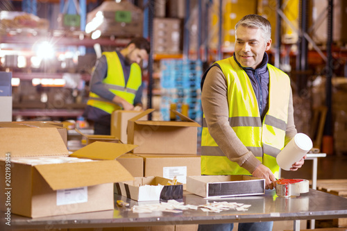Manual job. Nice hard working man standing at the table and preparing the package