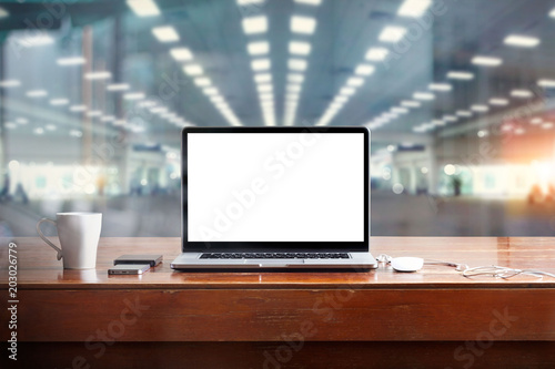 Laptop with blank white screen on table and workspace in office background © ipopba