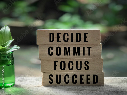 Motivational and inspirational quote - ‘Decide, commit, focus, succeed’ written on wooden blocks. With vintage styled background.