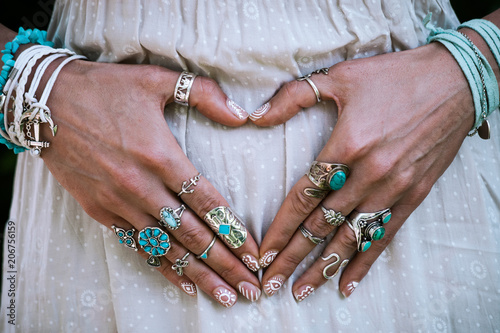 closeup of young woman hands in heart shape with lot of boho style jewrly, rings and bracelets outdoor © Coka