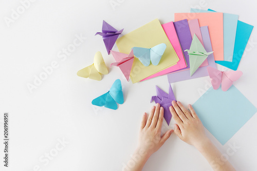 Children's hands do origami from colored paper on white background. lesson of origami © Anastasiia