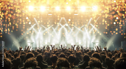 Concert venue crowded with clapping fans. Distress effects and lens flare are visible