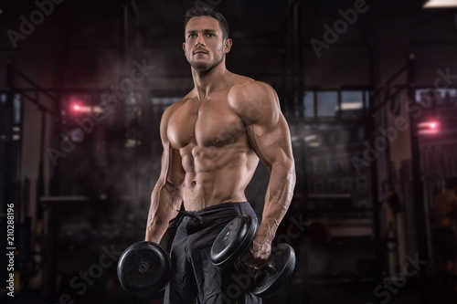 Young handsome sportsman bodybuilder weightlifter with an ideal body, after coaching poses in front of the camera, abdominal muscles, biceps triceps. In sportswear. © romanolebedev