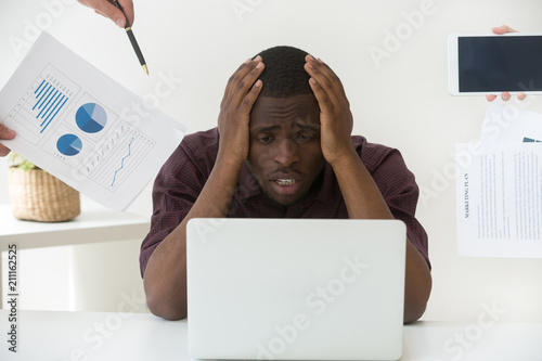 Stressed African American worker feeling despair, being tired at workplace having too much work, being annoyed by clients or colleagues, black employee fail to meet deadline, suffering from exhaustion