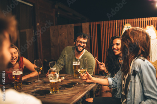 Group of friends drink beer on the terrace during summer night