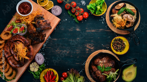 Food on a wooden table. Baked sausages, ribs and meatballs. Top view. Free space for your text.