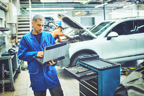 mechanic man with automotive diagnostic scanner and clipboard checking car system at workshop © 6okean
