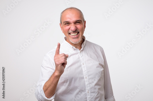 Satisfied mature hispanic man showing index fingers up, giving advice or recommendation