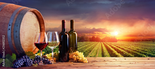 Bottles And Wineglasses With Grapes And Barrel In Rural Scene
