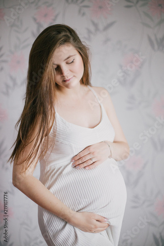 Young beautiful pregnant woman posing in a white dress © polinaloves