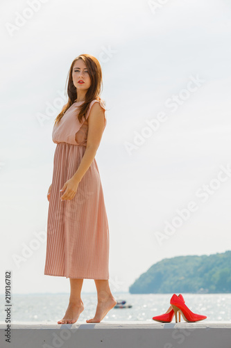 Woman wearing long light pink dress on jetty © Voyagerix