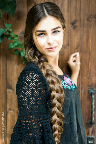 Girl in black dress with flax, lace, long braid, Russian beauty, rustic style, wooden background © yakovlevadaria