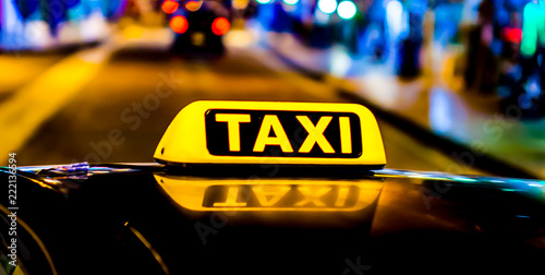 Night picture of a taxi car. Taxi sign on the car roof glowing in the dark