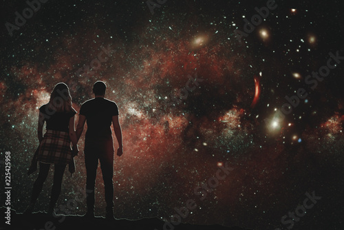 The silhouette of a lovers pair who looks at the night sky. A conceptual illustration of the silhouettes of people watching the cosmos. Boy and girl holding hands looking at the stars.
