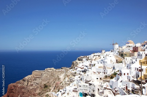 Romantic view of beautiful white washed buildings against blue sky, clouds and vivid sea in Santorini island, Oia, Greece © kayode