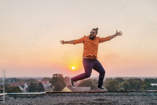 Picture of happy cheerful modern young man on roof top dancing and celebrating success and good news.