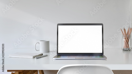 Blank white screen laptop with office supplies on white desk workspace.