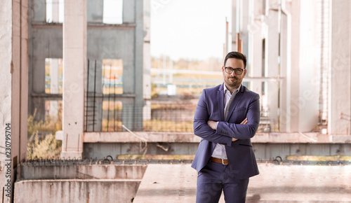 A successful handsome investor is satisfied because he bought an abandoned construction site.