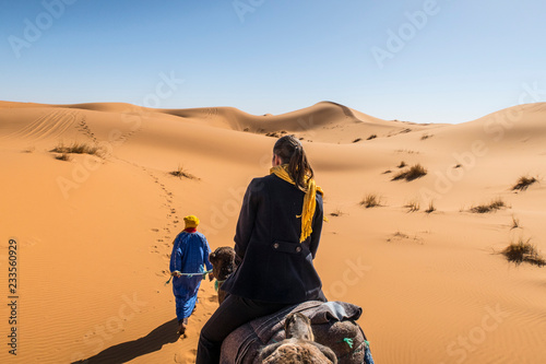 Berber nomad and a young girl riding camel in Sahara desert, Morocco © ivanka84