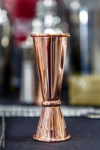 Copper jigger for cocktails is on the bar. © milanchikov