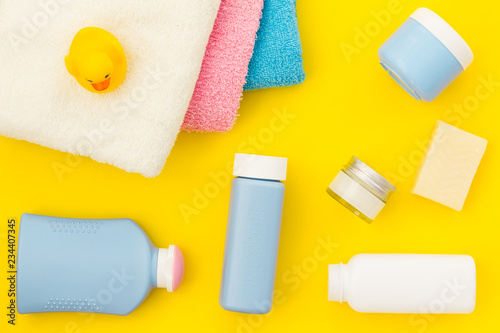 Shower accessories for child. Set with shampoo, towel, soap, gel, towel, brush and yellow rubber duck on yellow background top view pattern © 9dreamstudio