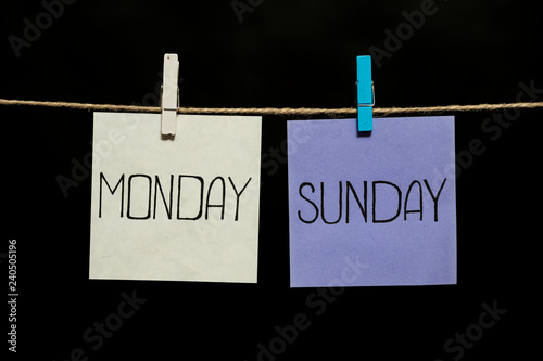 Copy space. Monday and sunday. Two colored sheets with the names of the days of the week. Stickers attached to a clothespin.