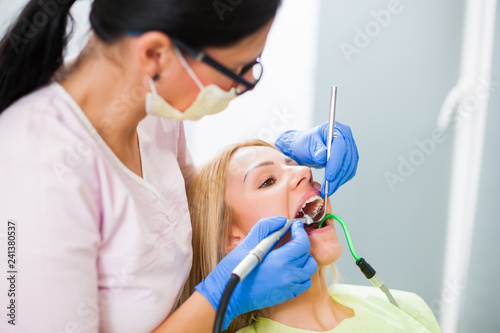 Young woman at dentist. Dentist is repairing her teeth. © djoronimo