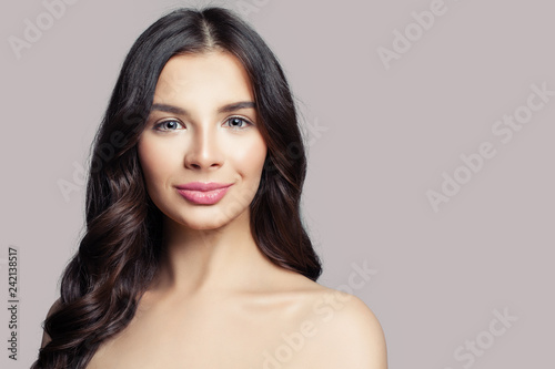 Beautiful woman face. Smiling female model with long curly hair on pink background © millaf