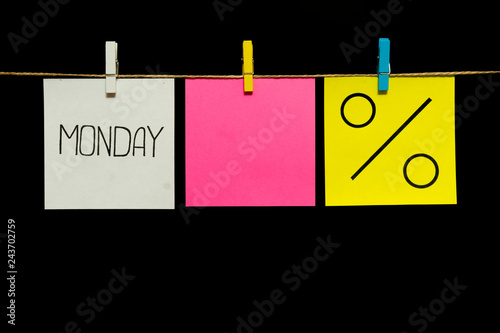 Copy space. Three stickers. On the left white sheet inscription Monday. In the center is a blank pink sheet. On the right yellow page is the percent symbol.