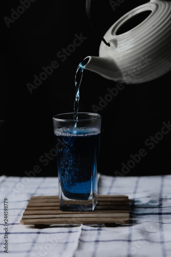 Butterfly Pea Tea. Pour into a glass of blue tea. Welding © Nickolay