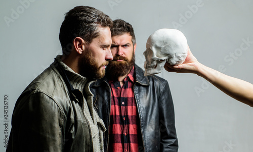 Man brutal bearded hipster looking at skull symbol of death. Overcome your fears. Be brave. Focused on breaking fear. Psychology concept. Human fears and courage. Looking deep into eyes of your fear